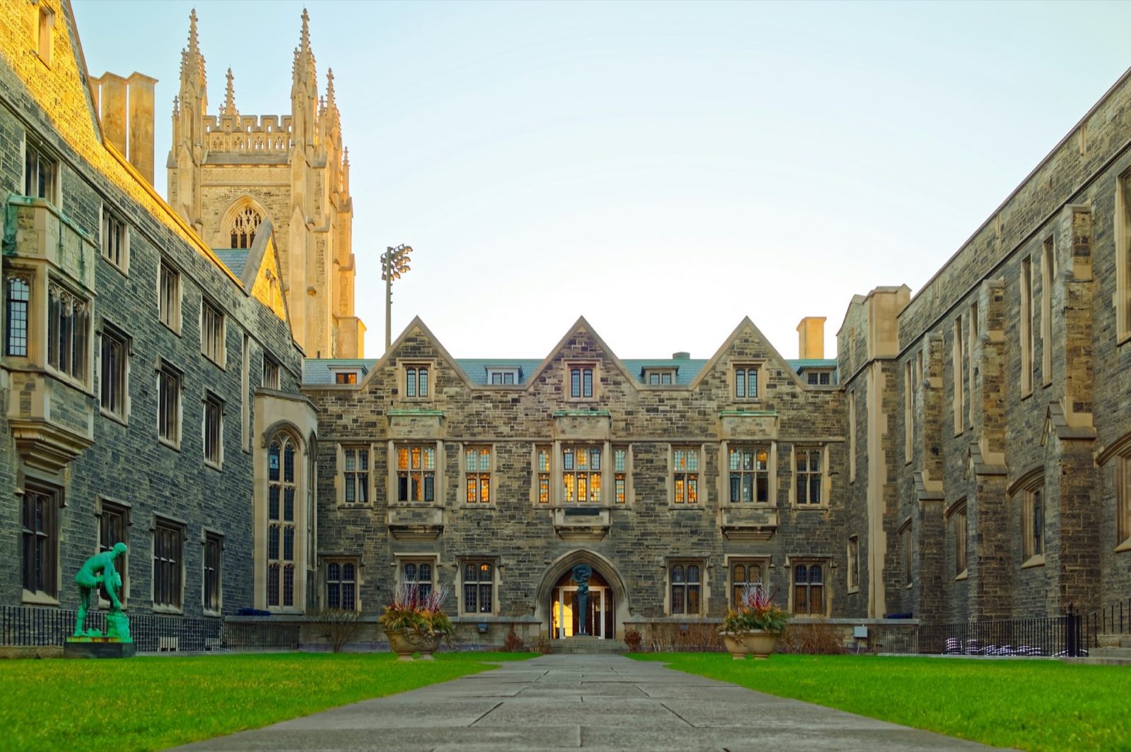 Stone university quadrangle at dusk, windows lit